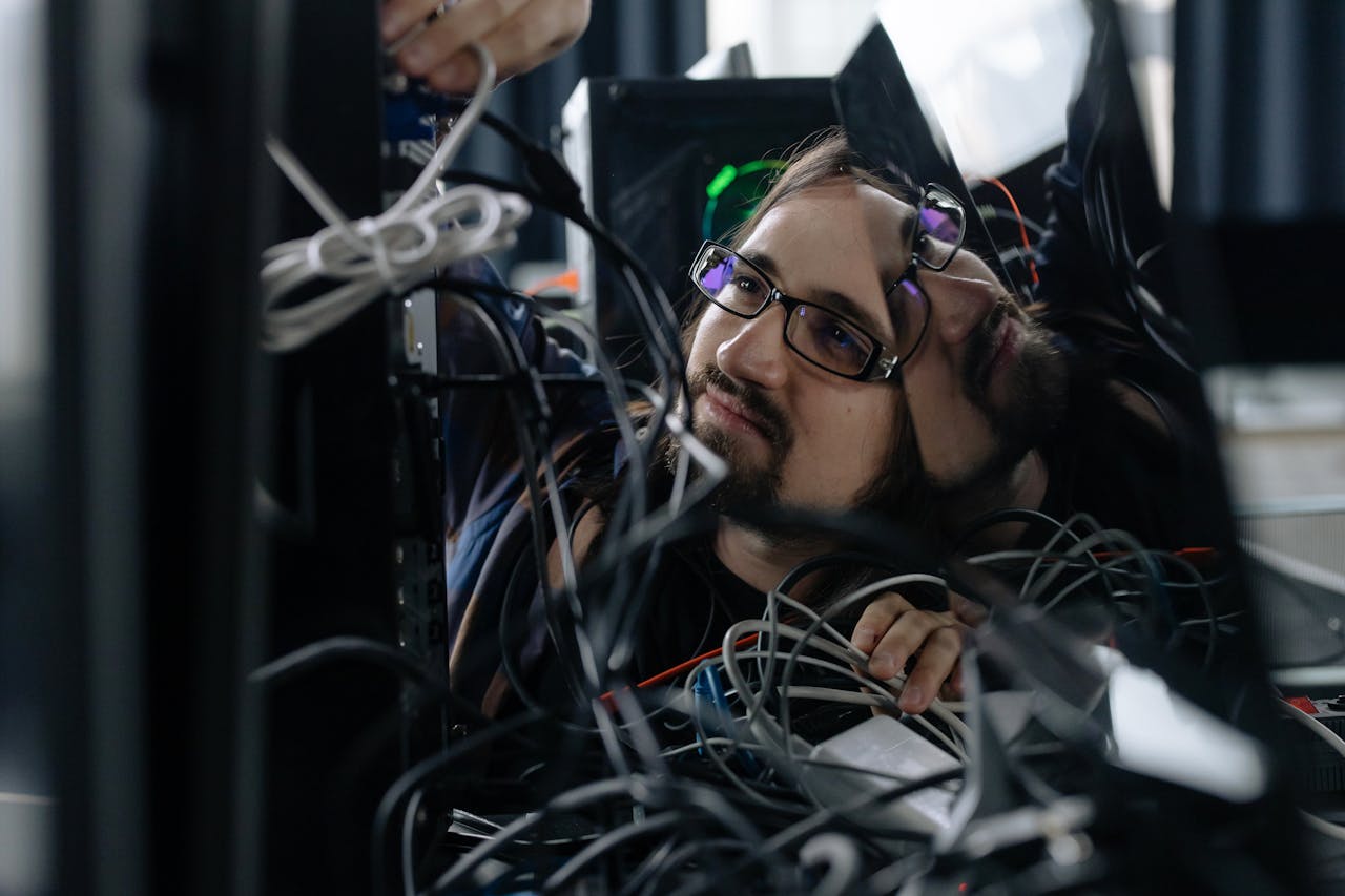 services-06 A skilled IT technician organizing tangled cables at his workstation in an office environment.